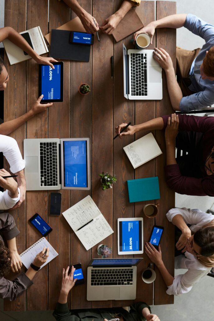 Overhead view of a diverse team in a business meeting using laptops and tablets.
